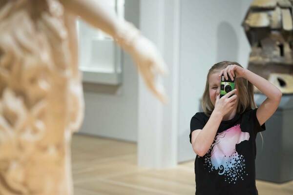 Kid taking a picture in the gallery of a sculpture