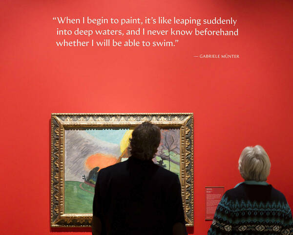 Image of two people looking at the painting Red Cloud in the gallery